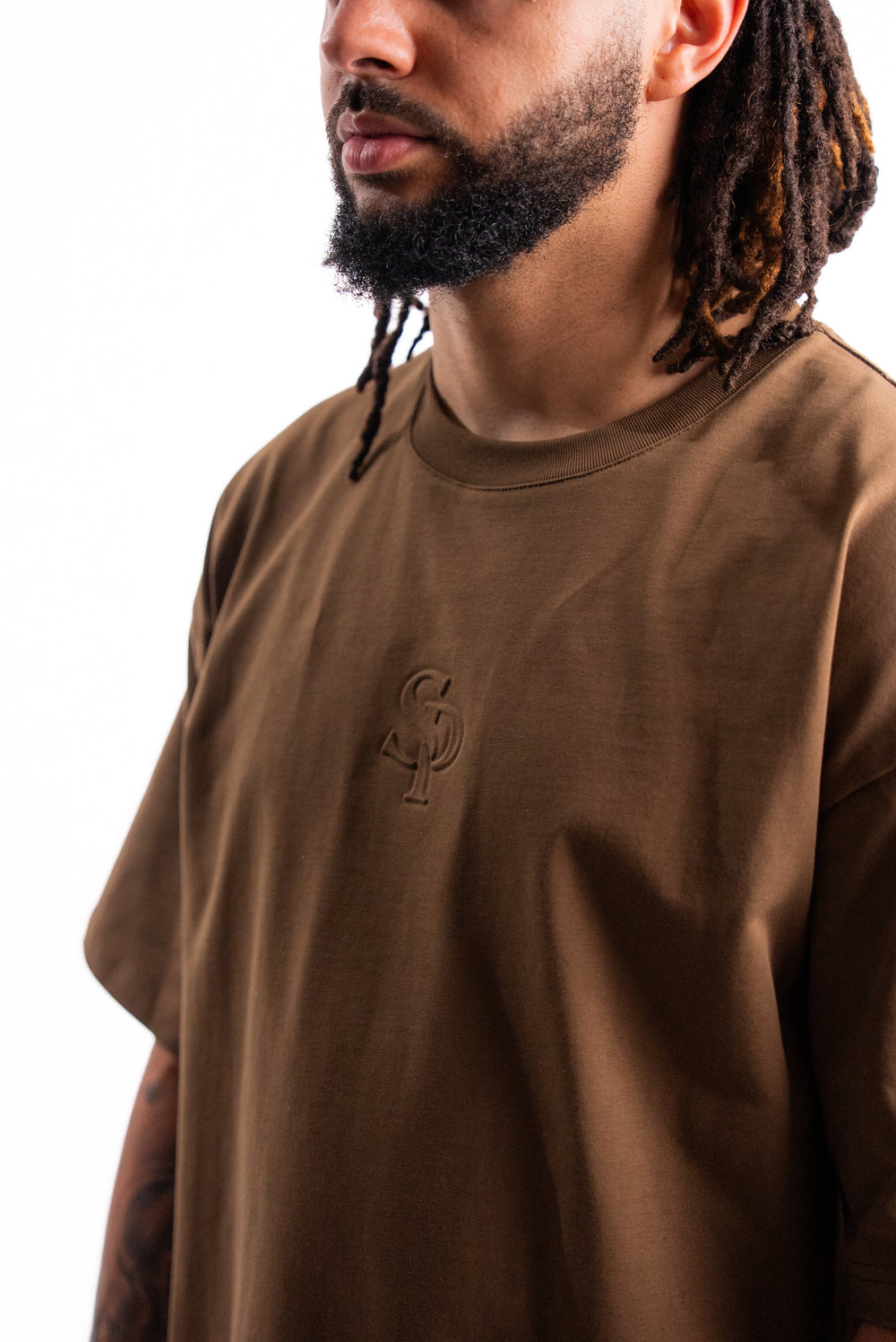 Chest and monogram detail of the SILNTPLAY Embossed Tee in Claystone